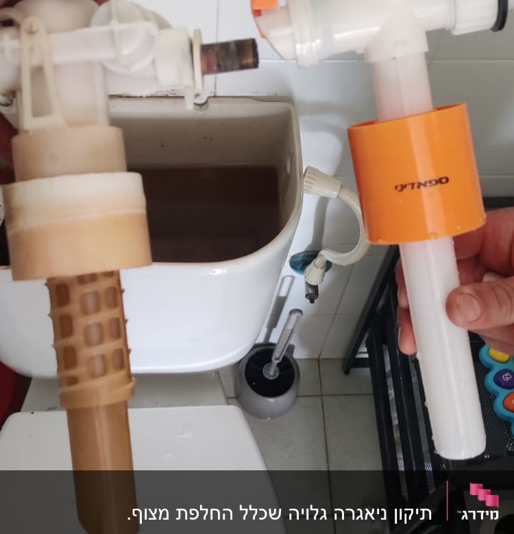 חלקי צנרת פלסטיק מוחזקים מעל מיכל שירותים פתוח